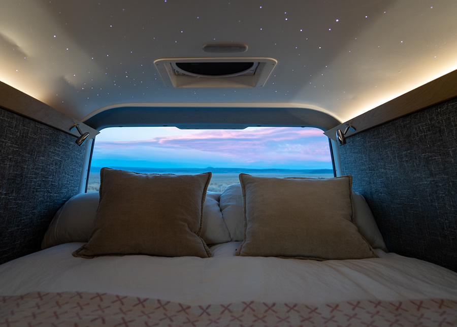 LED lights inlaid on the ceiling create a starry night above the bed; through the back window a pink and blue sunset